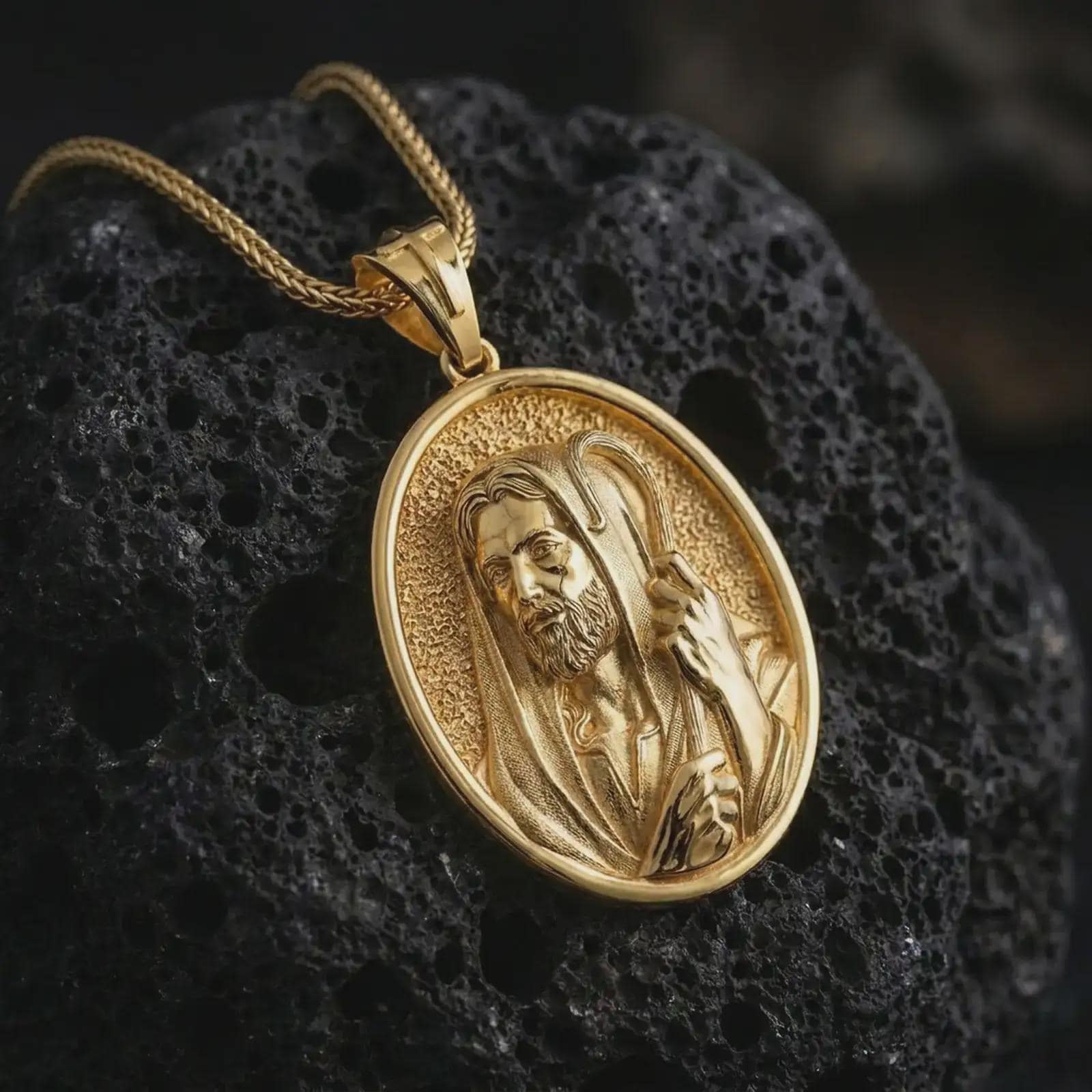Gold plated Jesus Christ Good Shepherd pendant necklace on textured volcanic rock, premium close-up studio composition emphasizing the Jesus portrait, shepherd staff, and sacred symbolism.