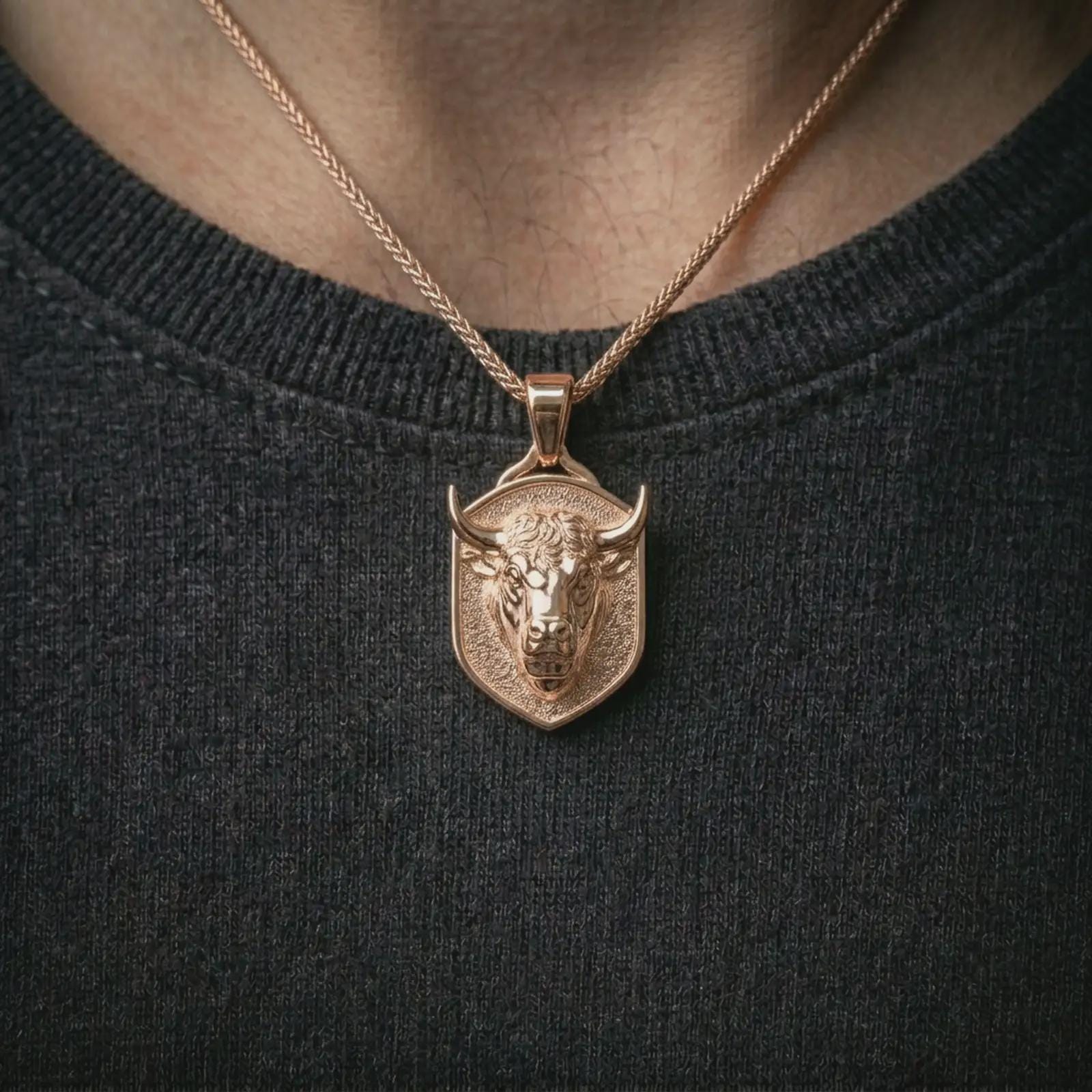 Rose gold plated bull head shield pendant necklace worn on the neck, presented in a close-up lifestyle shot with a refined zodiac-inspired aesthetic.