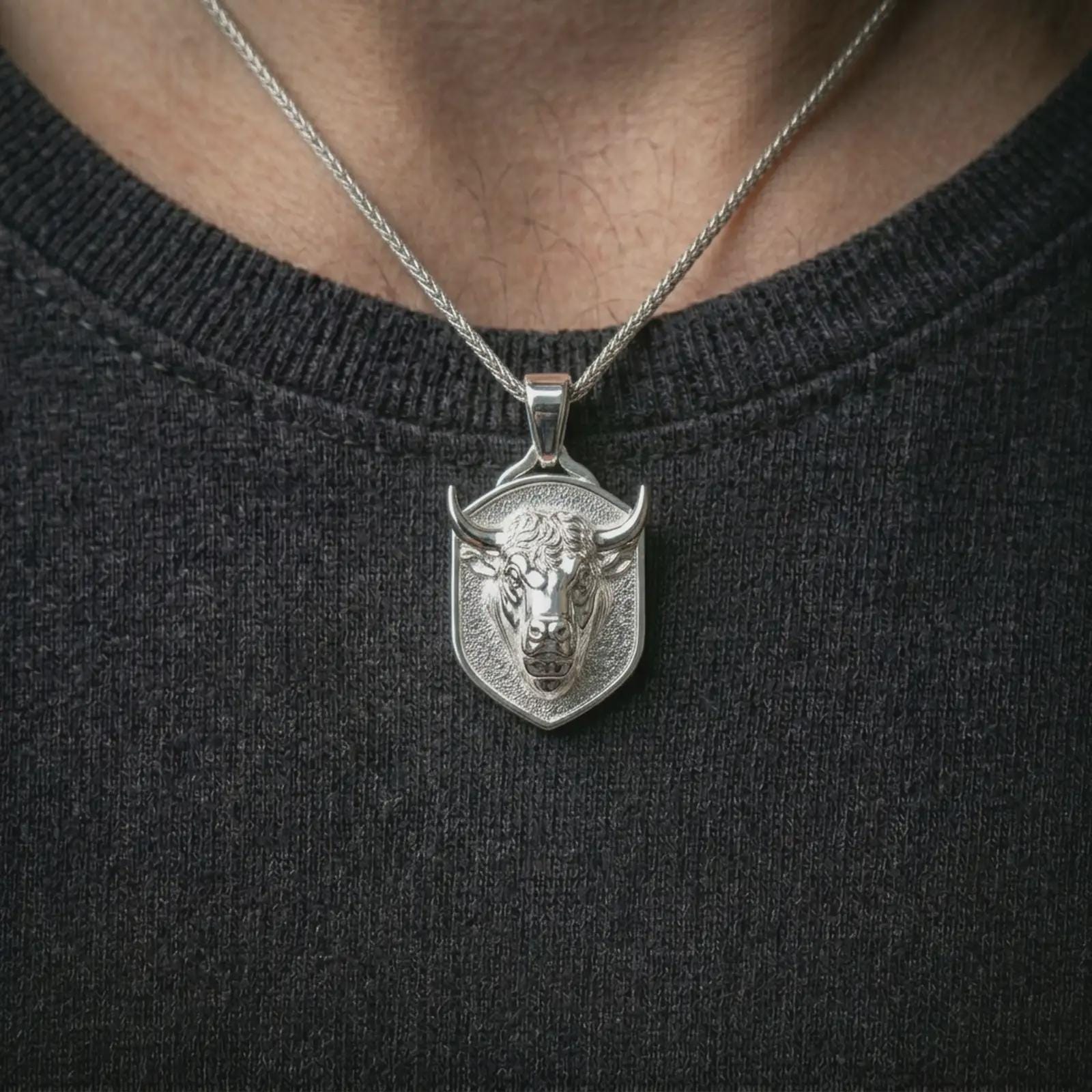 Polished silver bull head shield pendant necklace worn on the neck, shown against the chest in a clean and striking everyday wear composition.