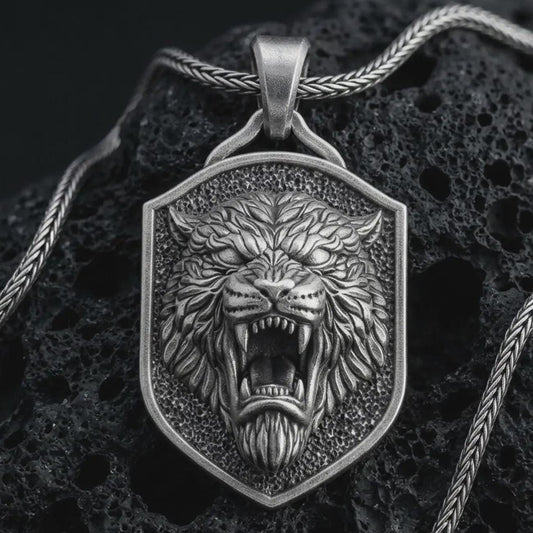Sterling silver roaring lion shield pendant necklace with an oxidized finish resting on textured volcanic rock, captured in a close-up premium studio composition.
