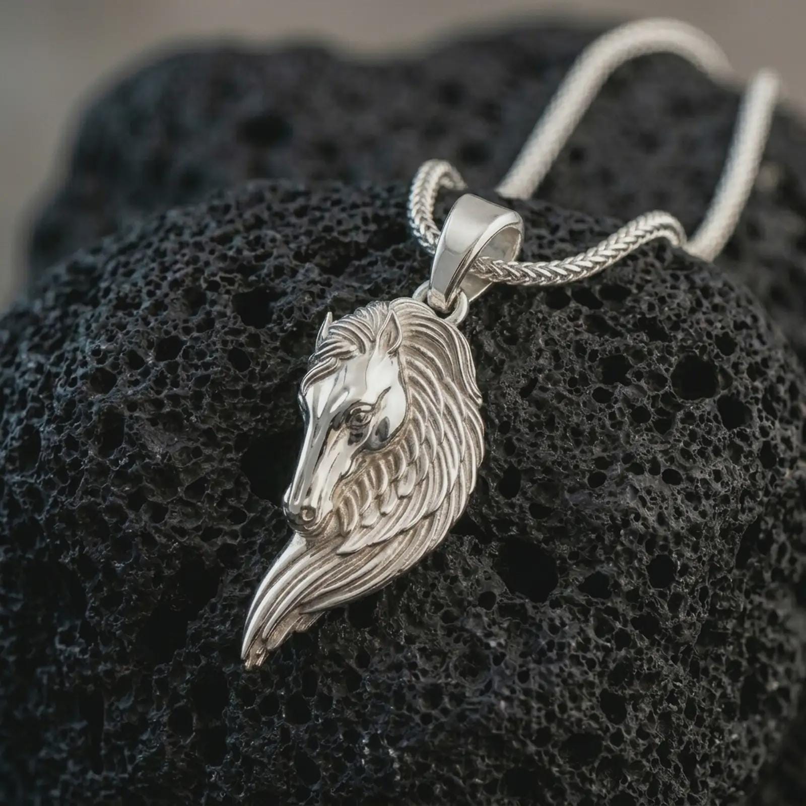 Polished silver Pegasus wing horse pendant necklace displayed on black volcanic rock, shown in a refined macro product shot with elongated horse head, flowing feathered wing detail, and elegant fantasy silhouette.