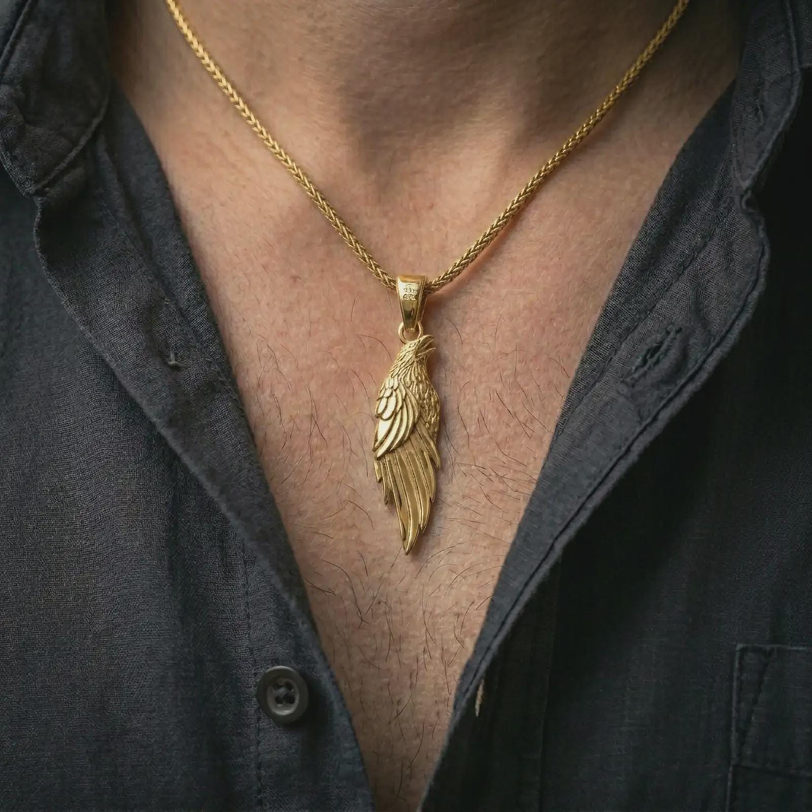 Gold plated raven pendant necklace worn on the neck, captured on a human model in a premium dark-toned lifestyle frame.