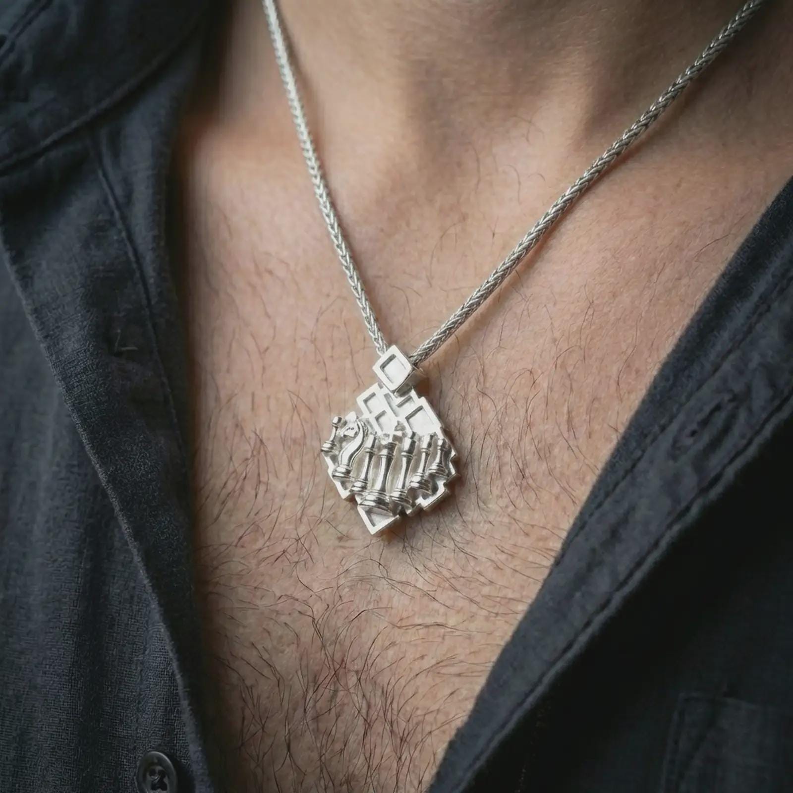Polished silver chessboard pendant necklace worn on the neck, shown against the chest in a clean and striking everyday wear composition.