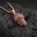 Load image into Gallery viewer, Rose gold plated gorilla head pendant necklace on dark volcanic rock, photographed in a detailed premium studio macro view.
