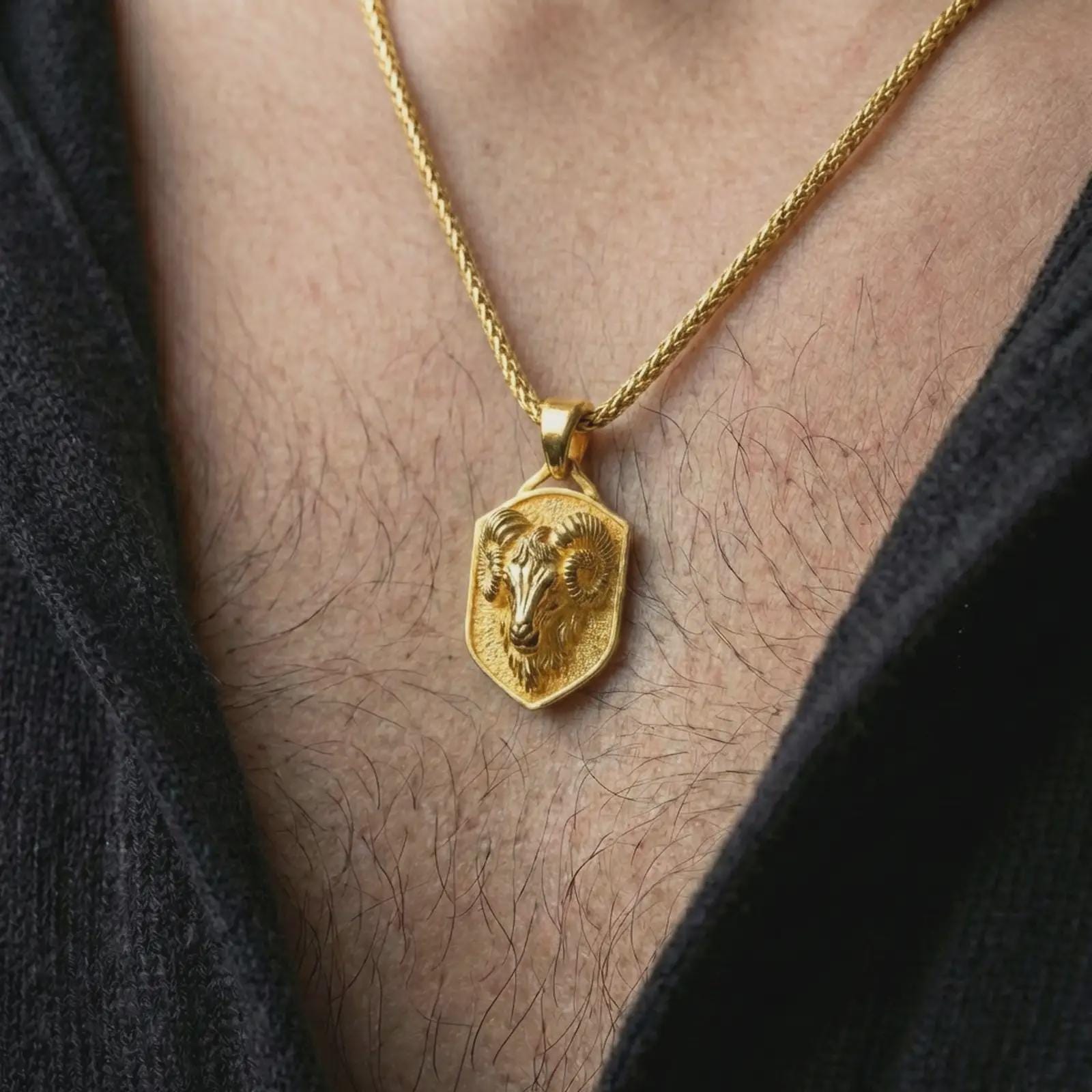 Gold plated ram head shield pendant necklace worn on the neck, captured on a human model in a premium dark-toned lifestyle frame.