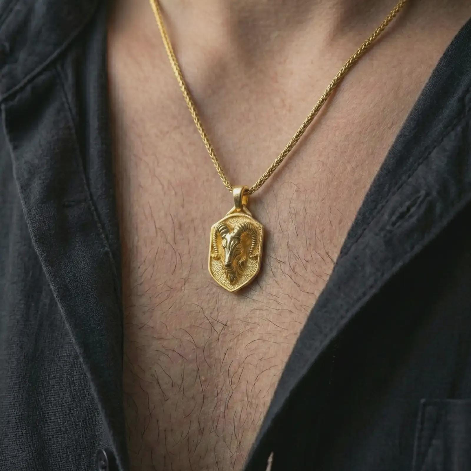 Ram head shield pendant necklace with a gold plated finish worn on the neck, captured in a premium lifestyle composition with the pendant centered on the chest.