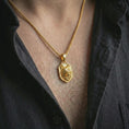Load image into Gallery viewer, Wolf shield pendant necklace with a gold plated finish worn on the neck, captured in a premium lifestyle composition with the pendant centered on the chest.
