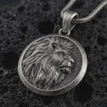 Load image into Gallery viewer, Sterling silver lion medallion pendant necklace with an oxidized finish resting on textured volcanic rock, captured in a close-up premium studio composition.
