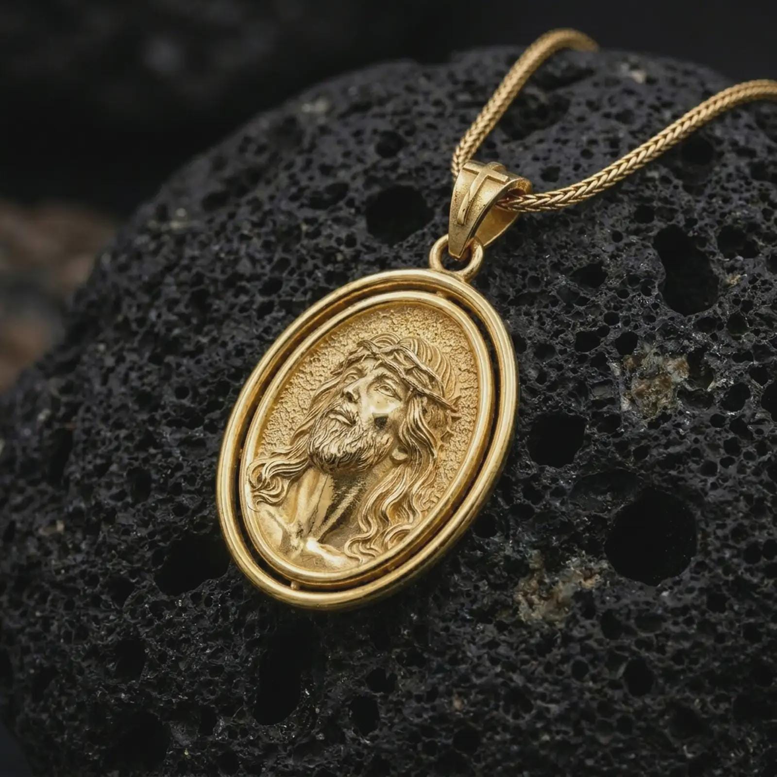 Gold plated spinning Jesus Christ pendant necklace on textured volcanic rock, premium close-up studio composition emphasizing the Jesus portrait, crown of thorns, and rotating frame design.