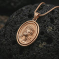 Load image into Gallery viewer, Rose gold plated spinning Jesus Christ pendant necklace on textured volcanic rock, detailed macro product shot with soft warm reflections and sacred Christian symbolism.
