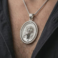 Load image into Gallery viewer, Polished silver spinning Jesus Christ pendant necklace worn on the chest, masculine lifestyle shot highlighting the Jesus portrait, crown of thorns, and bright silver finish.
