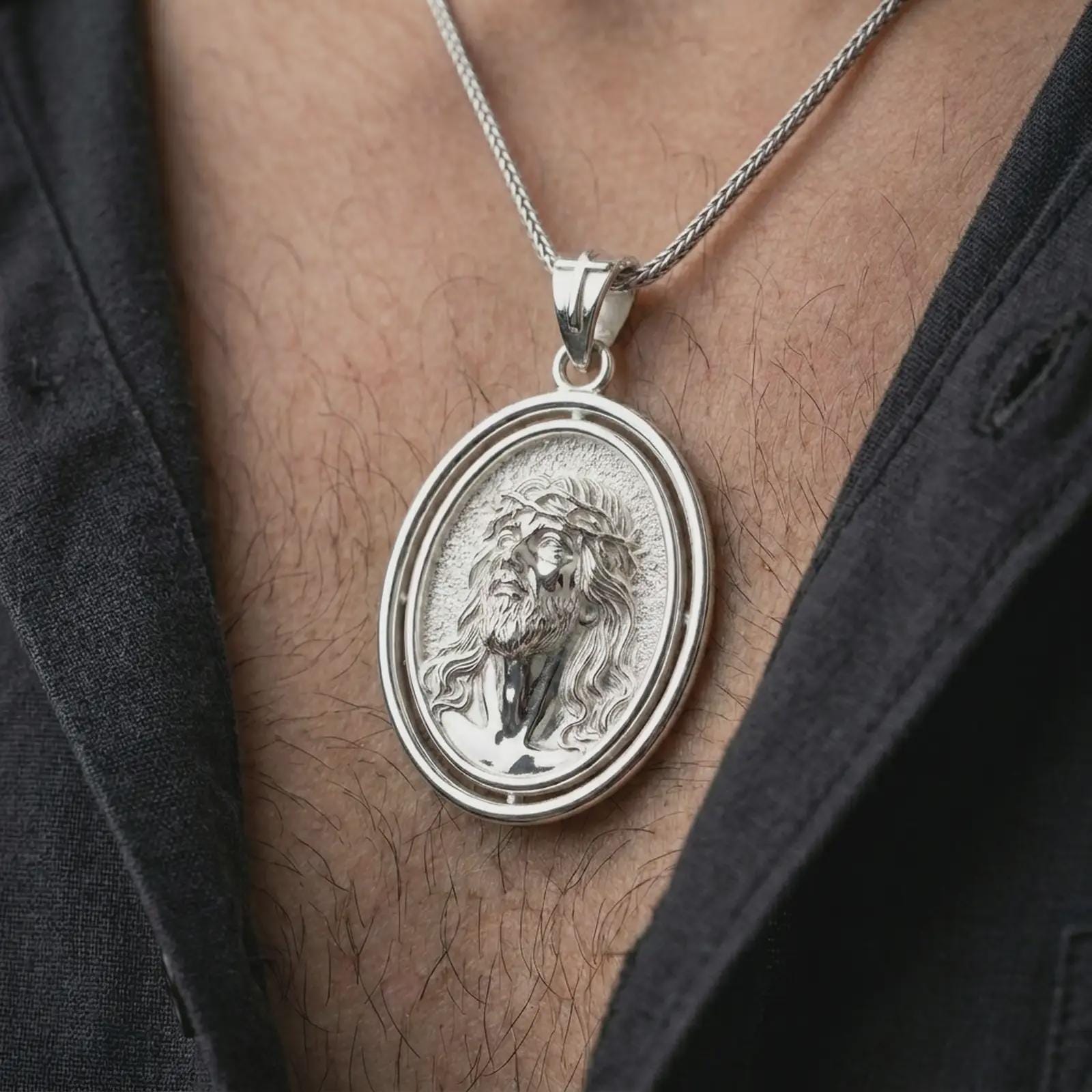 Polished silver spinning Jesus Christ pendant necklace worn on the chest, masculine lifestyle shot highlighting the Jesus portrait, crown of thorns, and bright silver finish.