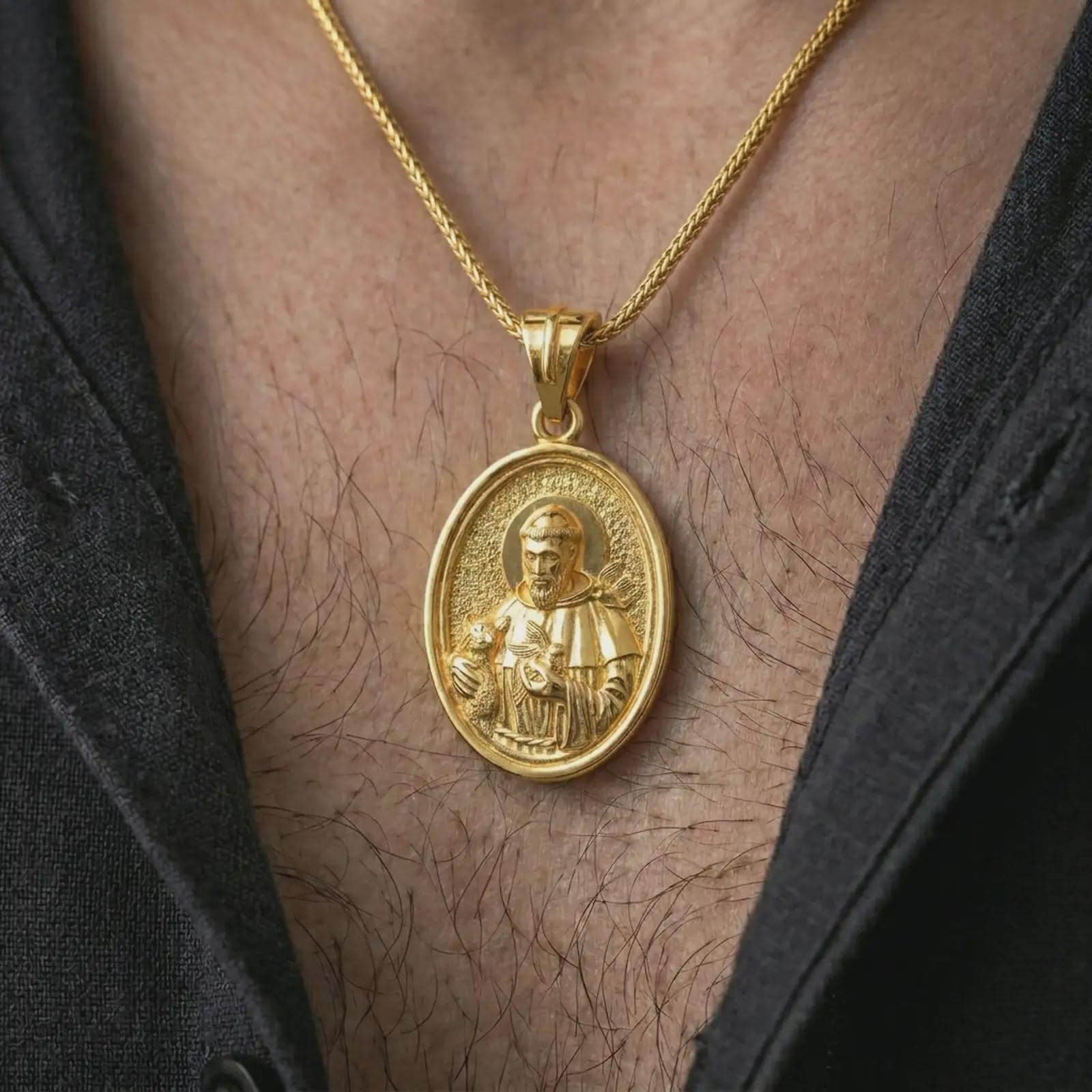 Gold plated Saint Francis pendant necklace worn on the chest, premium lifestyle jewelry photo with the Saint Francis medal centered on a spiga chain.