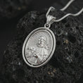 Load image into Gallery viewer, Polished silver Saint Francis pendant necklace on textured volcanic rock, centered macro jewelry photo with detailed Catholic medal relief and bright silver highlights.
