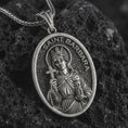 Load image into Gallery viewer, Oxidized Saint Barbara pendant necklace on textured volcanic rock, close-up studio shot highlighting the crowned saint relief, cross, tower detail, and antique silver contrast.
