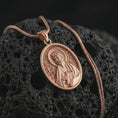 Load image into Gallery viewer, Rose gold plated Saint James the Apostle pendant necklace on textured volcanic rock, detailed macro product shot with soft warm reflections and devotional Saint James design.

