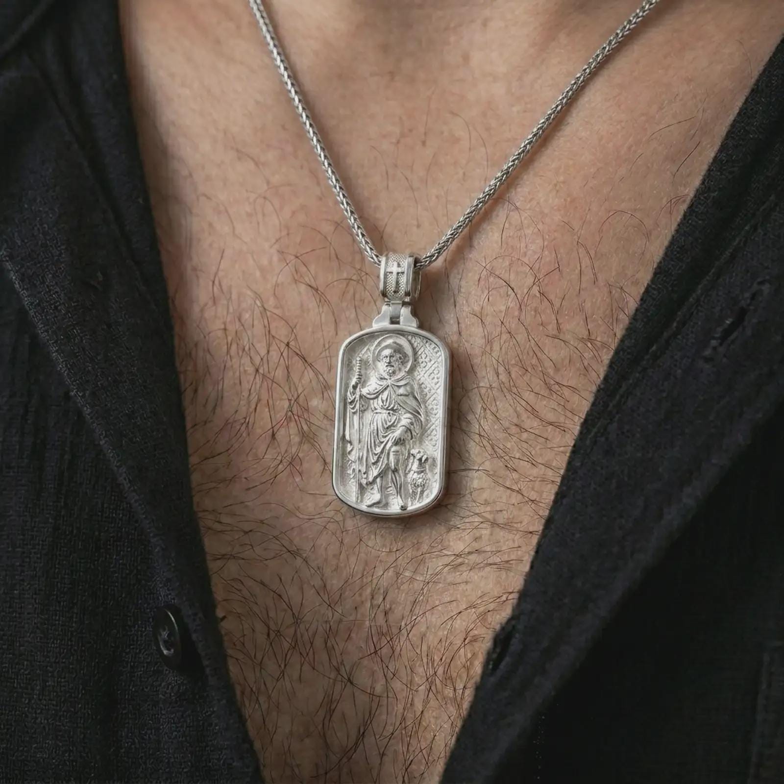 Polished silver Saint Roch dog tag pendant necklace worn on the chest, masculine lifestyle shot highlighting the pilgrim saint relief, staff, dog detail, and bright silver finish.
