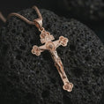 Load image into Gallery viewer, Rose gold plated crucifix pendant necklace on porous black volcanic rock, featured in a detailed macro image with the crucified Christ figure and elegant ornamental accents.
