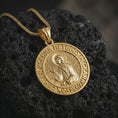 Load image into Gallery viewer, Gold plated Saint Xenia pendant necklace presented on textured black volcanic stone, captured in a luxury macro composition emphasizing the religious medal silhouette and saint icon details.
