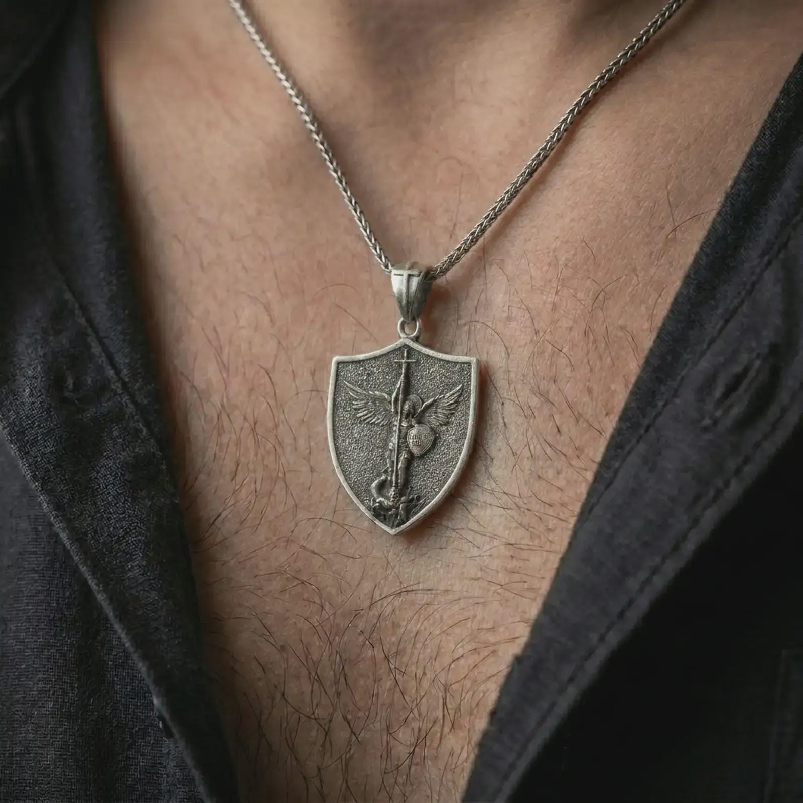 Oxidized Saint Michael pendant necklace worn on the neck, styled in a dark lifestyle image that presents the archangel medal as a bold symbol of faith and protection.