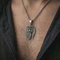 Load image into Gallery viewer, Oxidized angel warrior pendant necklace worn on the neck, styled in a dark lifestyle image that presents the winged guardian figure as a symbol of strength, faith, and spiritual protection.
