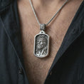 Load image into Gallery viewer, Polished silver INRI Jesus pendant necklace worn on the chest, masculine lifestyle shot highlighting the crown of thorns relief, INRI detail, and bright silver finish.

