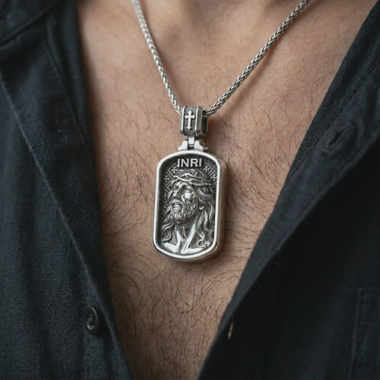 Polished silver INRI Jesus pendant necklace worn on the chest, masculine lifestyle shot highlighting the crown of thorns relief, INRI detail, and bright silver finish.