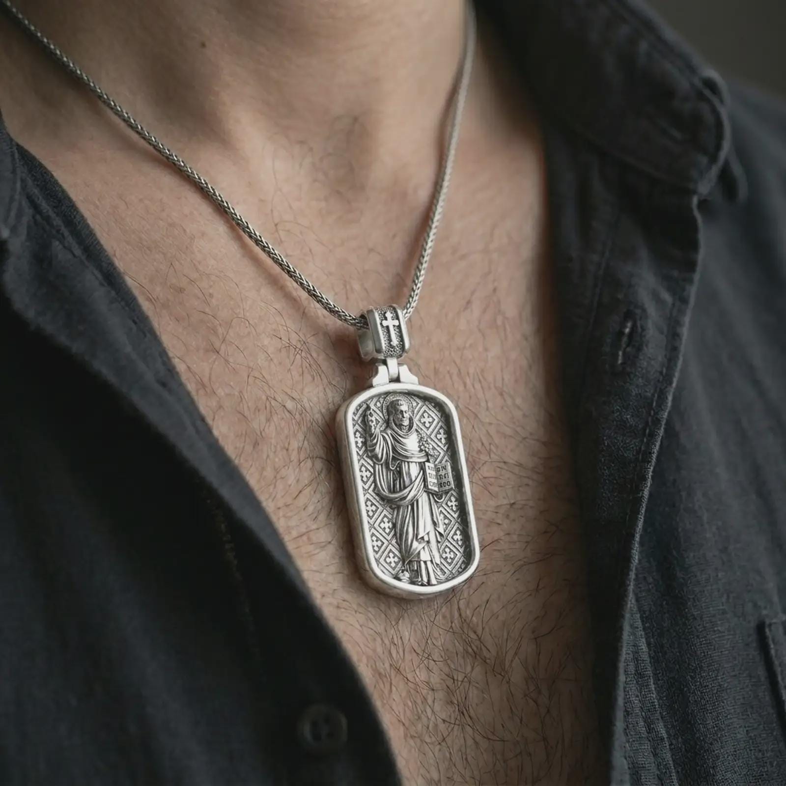 Polished silver Saint Dominic dog tag pendant necklace worn on the chest, masculine lifestyle shot highlighting the saint relief, book detail, lily, and bright silver finish.