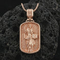 Load image into Gallery viewer, Rose gold plated Saint Dominic dog tag pendant necklace on textured volcanic rock, detailed macro product shot with soft warm reflections and devotional Saint Dominic design.
