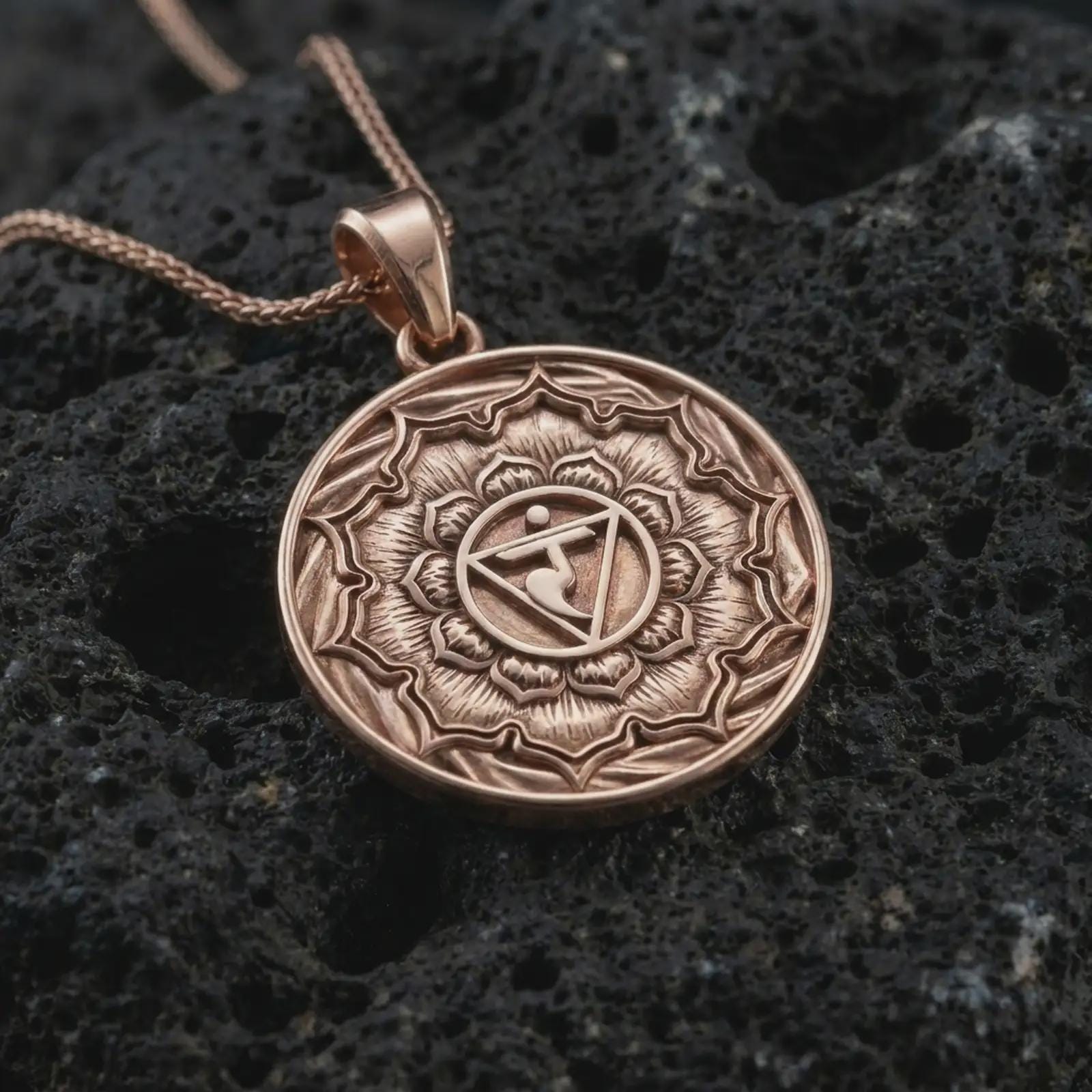 Rose gold plated Manipura chakra pendant necklace on textured volcanic rock, detailed macro product shot with soft warm reflections and spiritual mandala symbolism.