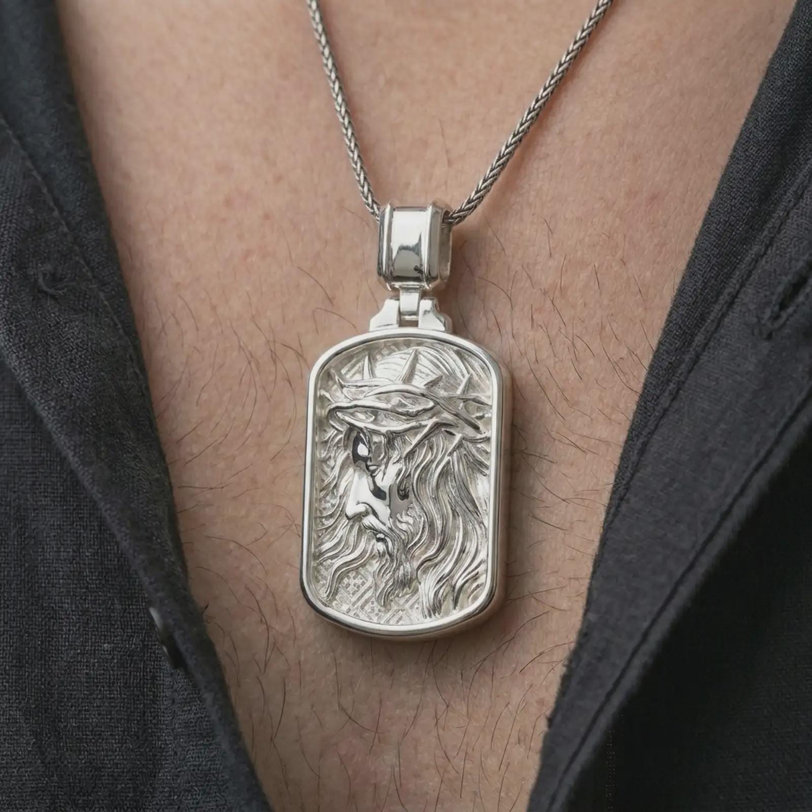 Polished silver crucified Jesus dog tag pendant necklace worn on the chest, masculine lifestyle shot highlighting the side-profile Christ relief, crown of thorns, and bright silver finish.