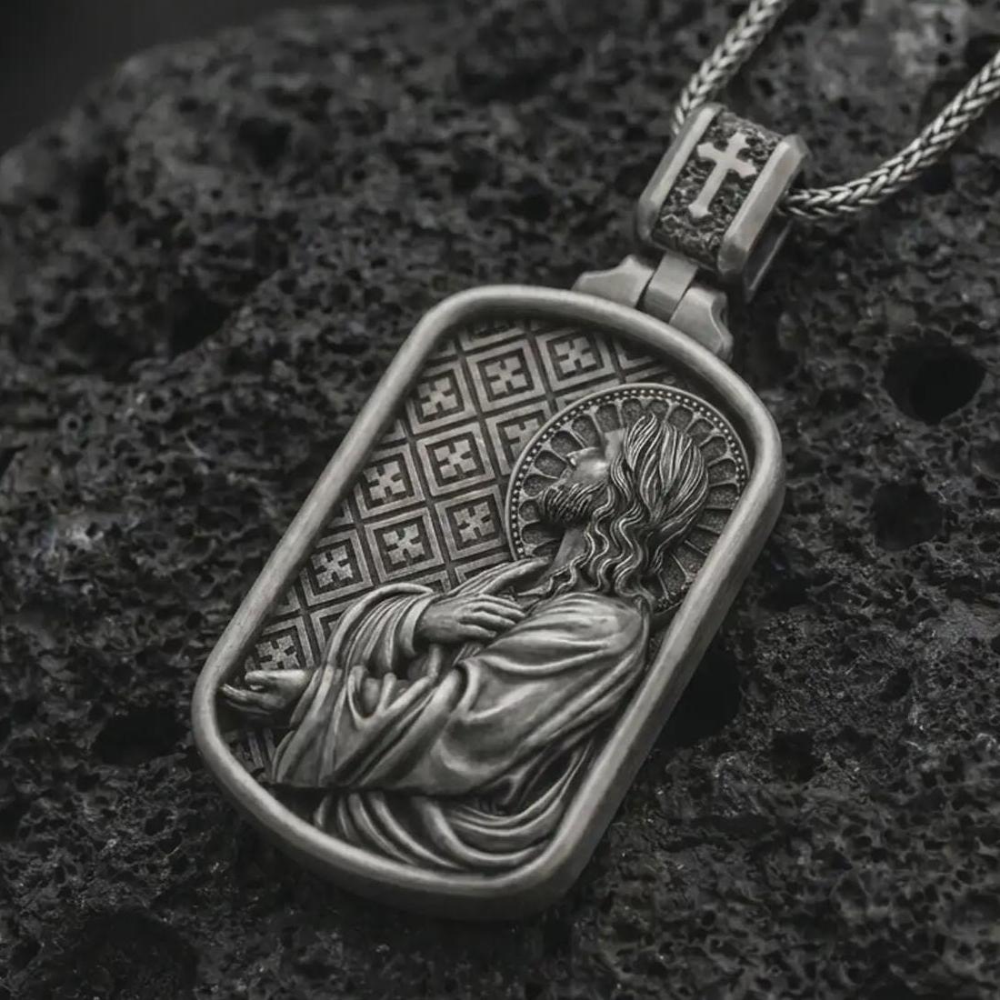 Oxidized Jesus prayer dog tag pendant necklace on textured volcanic rock, close-up studio shot highlighting the side-profile Christ relief, halo, prayer pose, and antique silver contrast.