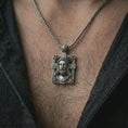 Load image into Gallery viewer, A Jesus crucifix pendant in an oxidized finish worn on the neck on a chain in a clean lifestyle close-up.
