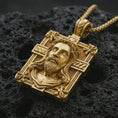 Load image into Gallery viewer, A Jesus crucifix pendant in a gold plated finish resting on porous volcanic rock in a premium macro studio shot.
