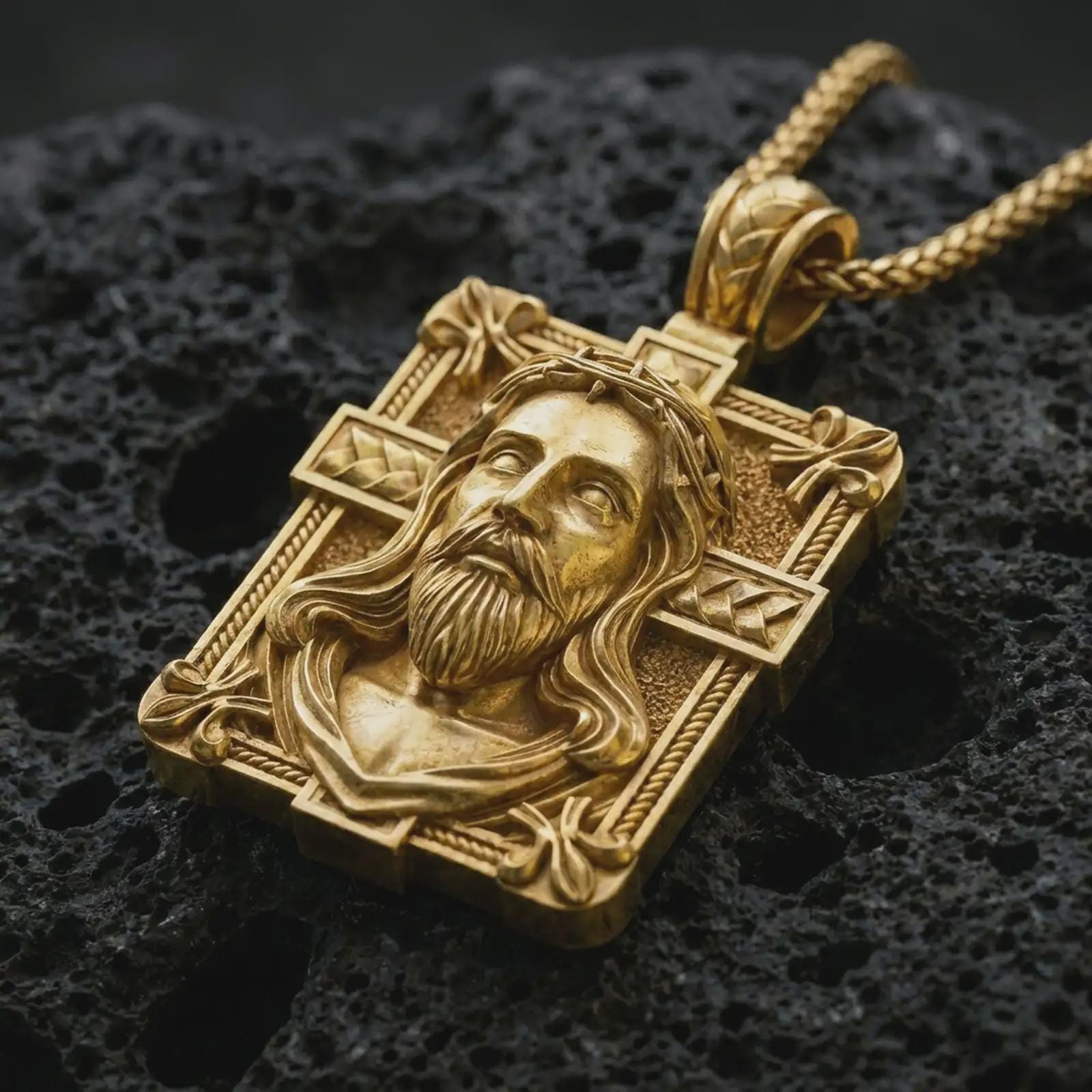A Jesus crucifix pendant in a gold plated finish resting on porous volcanic rock in a premium macro studio shot.