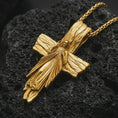 Load image into Gallery viewer, Gold plated Jesus cross pendant necklace on textured volcanic rock, premium close-up studio composition emphasizing the wooden cross texture, Jesus figure, and sacred heart rays.
