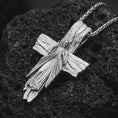 Load image into Gallery viewer, Polished silver Jesus cross pendant necklace on textured volcanic rock, centered macro jewelry photo with detailed Christ relief, flowing robe, and bright silver highlights.
