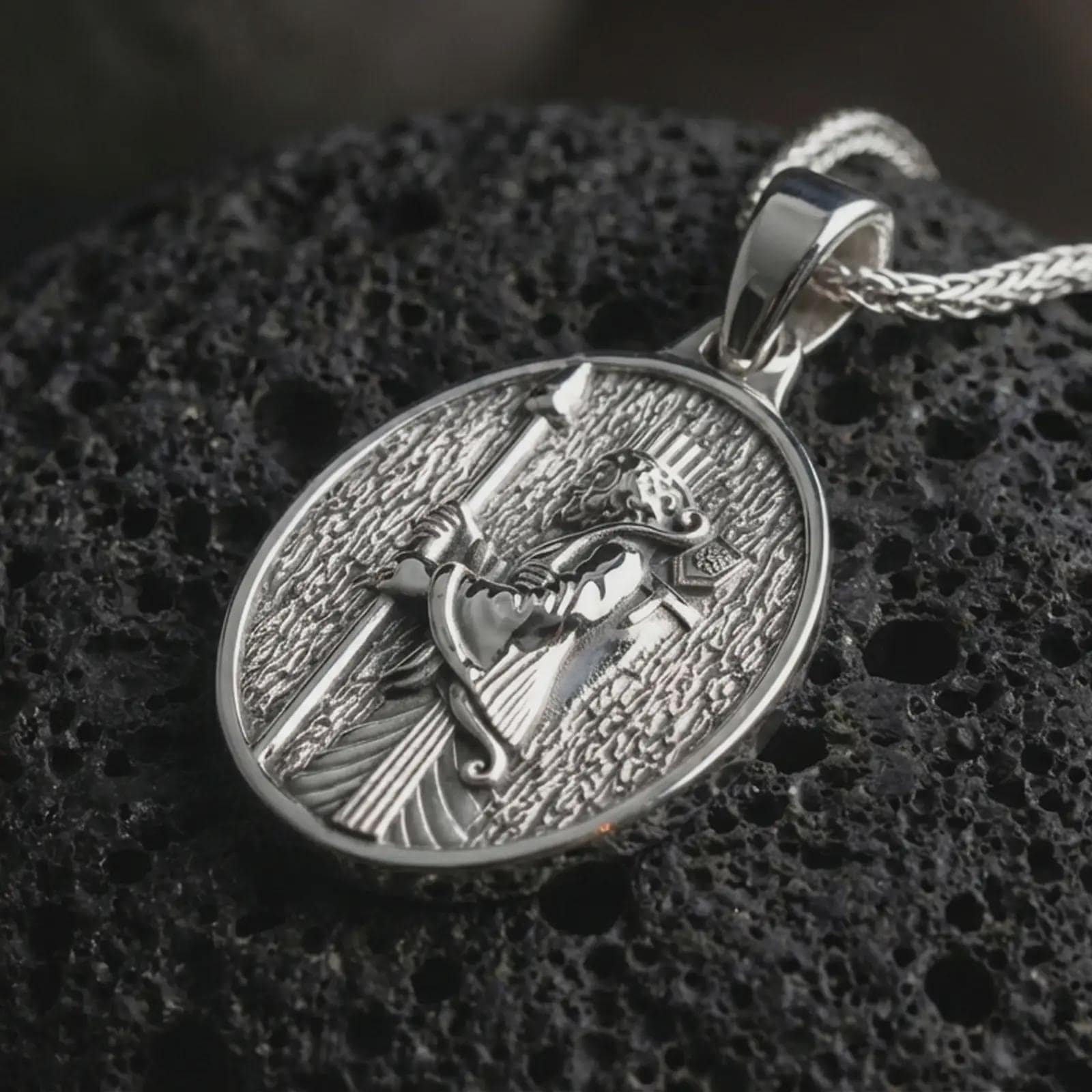 Polished silver Achaemenid soldier pendant necklace displayed on black volcanic rock, shown in a refined macro product shot highlighting the ancient warrior profile, long spear, and engraved background texture.