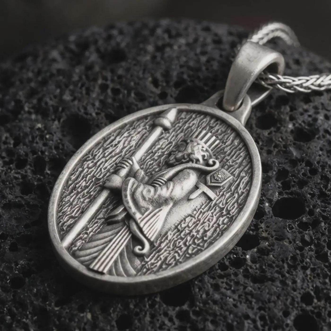 Sterling silver Achaemenid soldier pendant necklace with an oxidized finish resting on textured volcanic rock, captured in a close-up premium studio composition with a spear-bearing Persian warrior in oval relief.