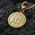 Load image into Gallery viewer, Gold plated Tiberius coin pendant necklace photographed on porous black volcanic stone, emphasizing the imperial side-profile relief and engraved ancient Roman lettering in a luxury jewelry composition.
