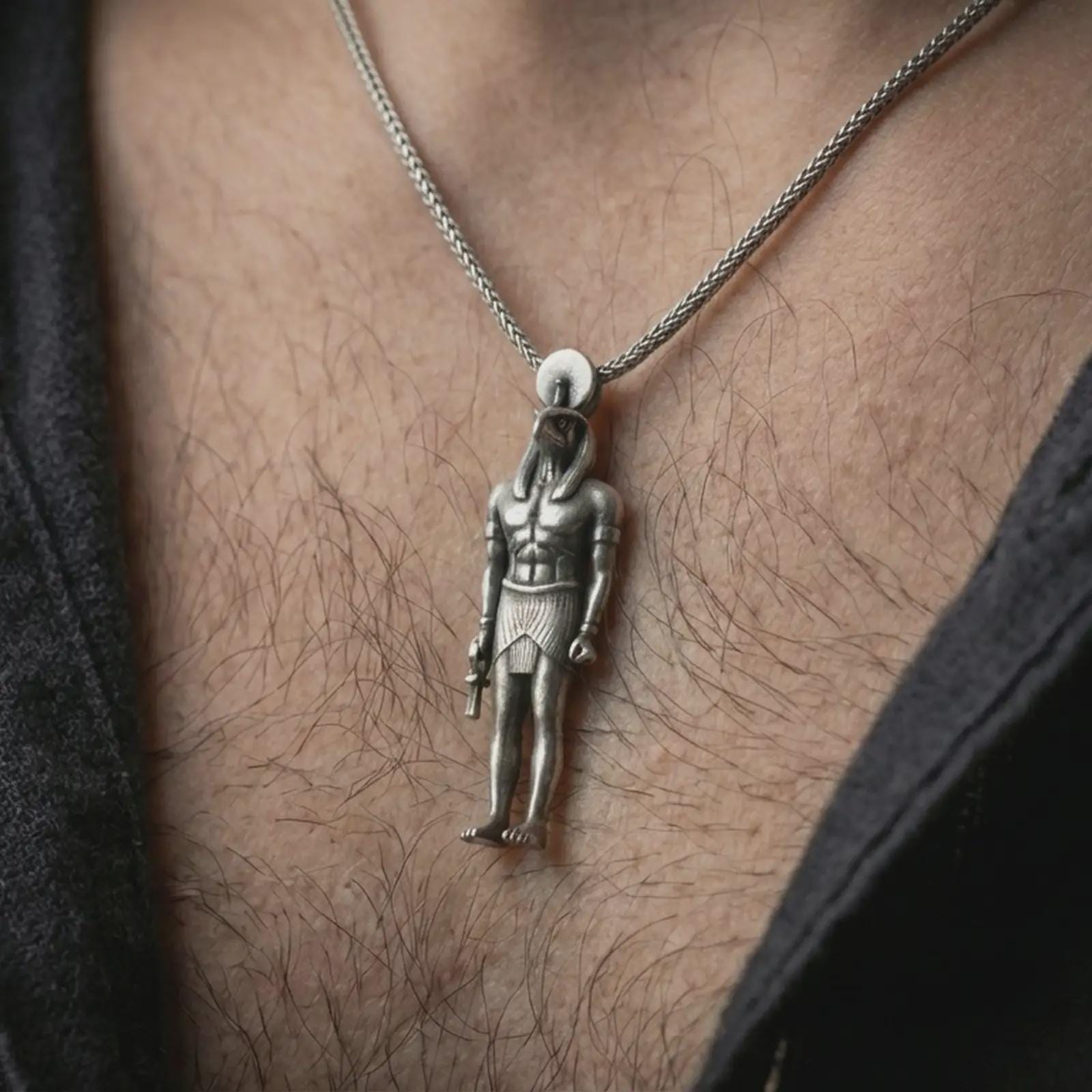 Oxidized Ra amulet pendant necklace worn on the neck, styled in a dark lifestyle image that presents the Egyptian god pendant as a bold symbolic and historical statement piece.