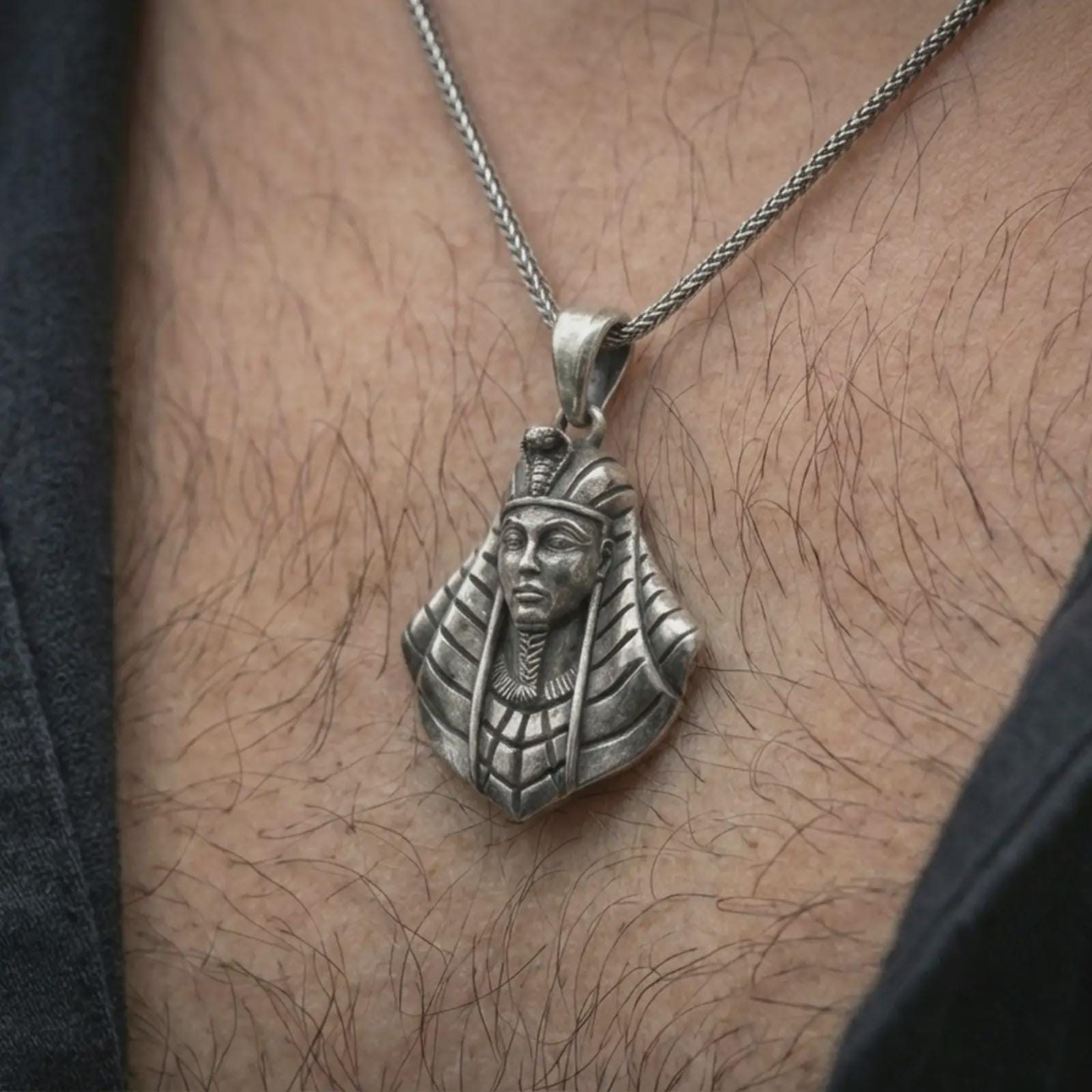 Oxidized Tutankhamun pendant necklace worn on the neck, styled in a dark lifestyle image that presents the Egyptian pharaoh pendant as a bold historical and symbolic statement piece.