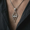 Load image into Gallery viewer, Polished silver Skyrim dragon pendant necklace worn on the chest, masculine lifestyle shot highlighting the angular dragon design and bright silver finish.
