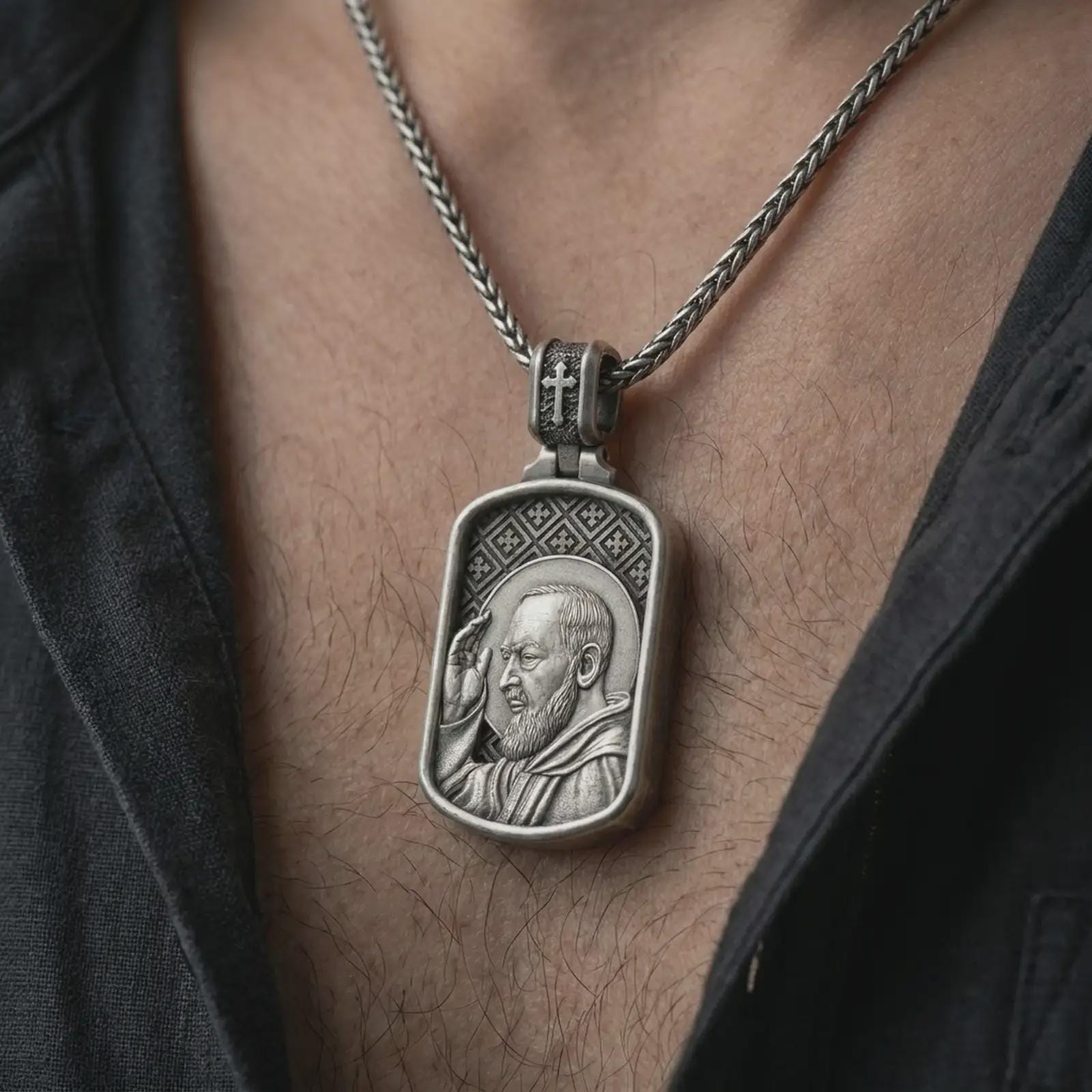 Oxidized Saint Padre Pio dog tag pendant necklace worn on the chest, close-up lifestyle jewelry photo showing the Christian medallion on a spiga chain with dark clothing.