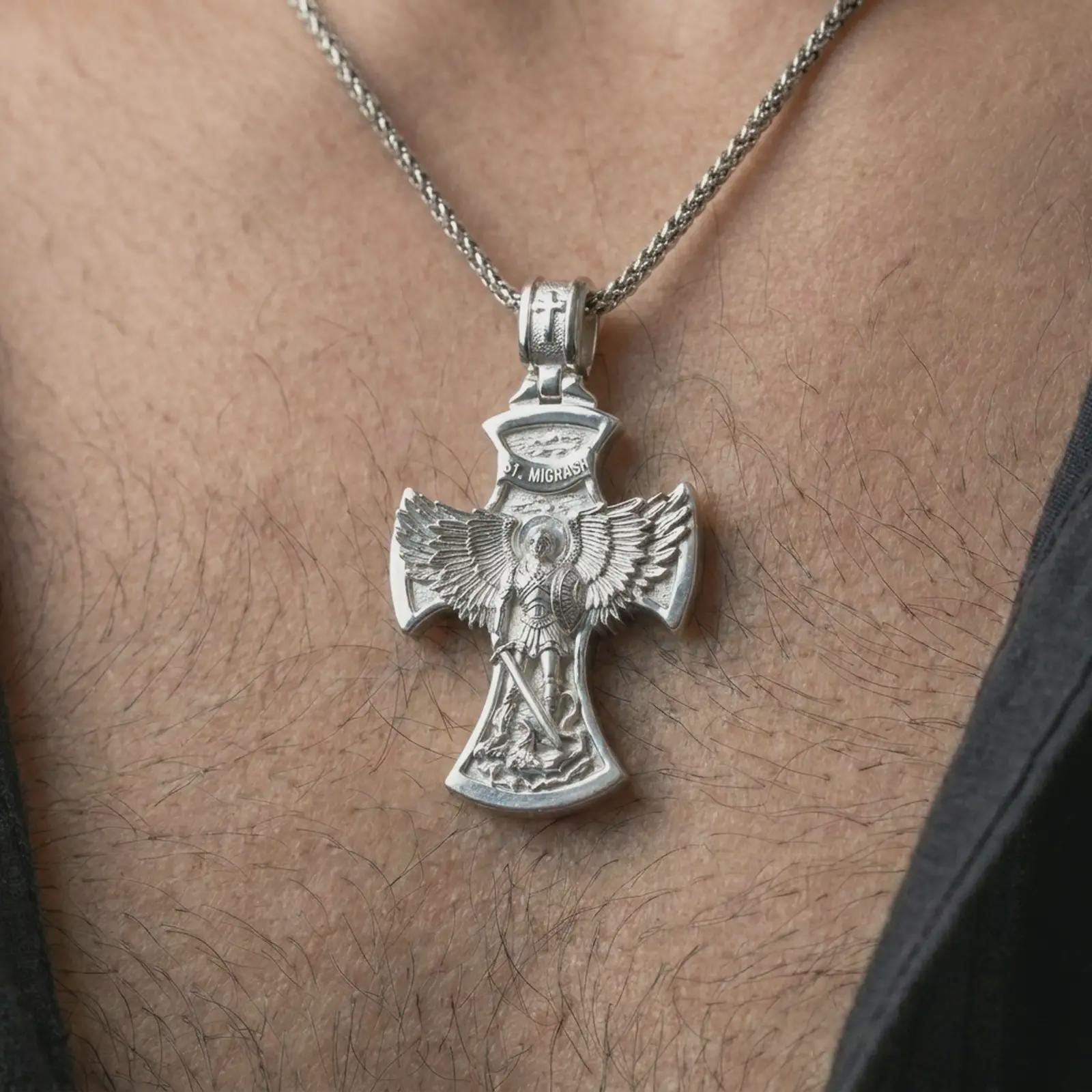 Polished silver Saint Michael cross pendant necklace worn on the chest, masculine lifestyle shot highlighting the angel wings, sword detail, and bright silver finish.