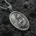 Load image into Gallery viewer, Oxidized Jesus Christ prayer pendant necklace on textured volcanic rock, close-up studio shot highlighting the praying Christ relief, radiant light detail, halo, and antique silver contrast.
