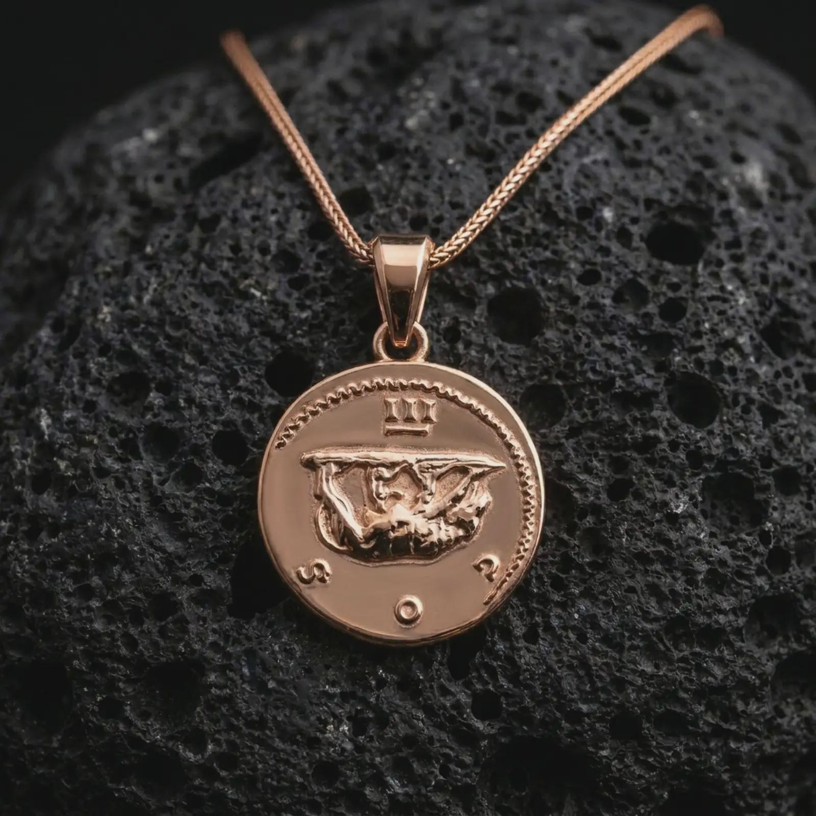 Rose gold plated Emperor Augustus coin pendant necklace presented on textured volcanic stone, showcasing the round Roman coin silhouette and refined emperor relief in a macro studio shot.