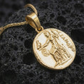 Load image into Gallery viewer, Gold plated Alexander the Great coin pendant necklace photographed on porous black volcanic stone, emphasizing the classical warrior motif and ancient coin silhouette in a refined luxury jewelry composition.
