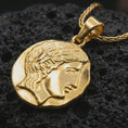 Load image into Gallery viewer, Gold plated ancient Greek coin pendant necklace presented on porous black volcanic stone, photographed in a refined close-up image emphasizing the goddess-like portrait and historic coin silhouette.
