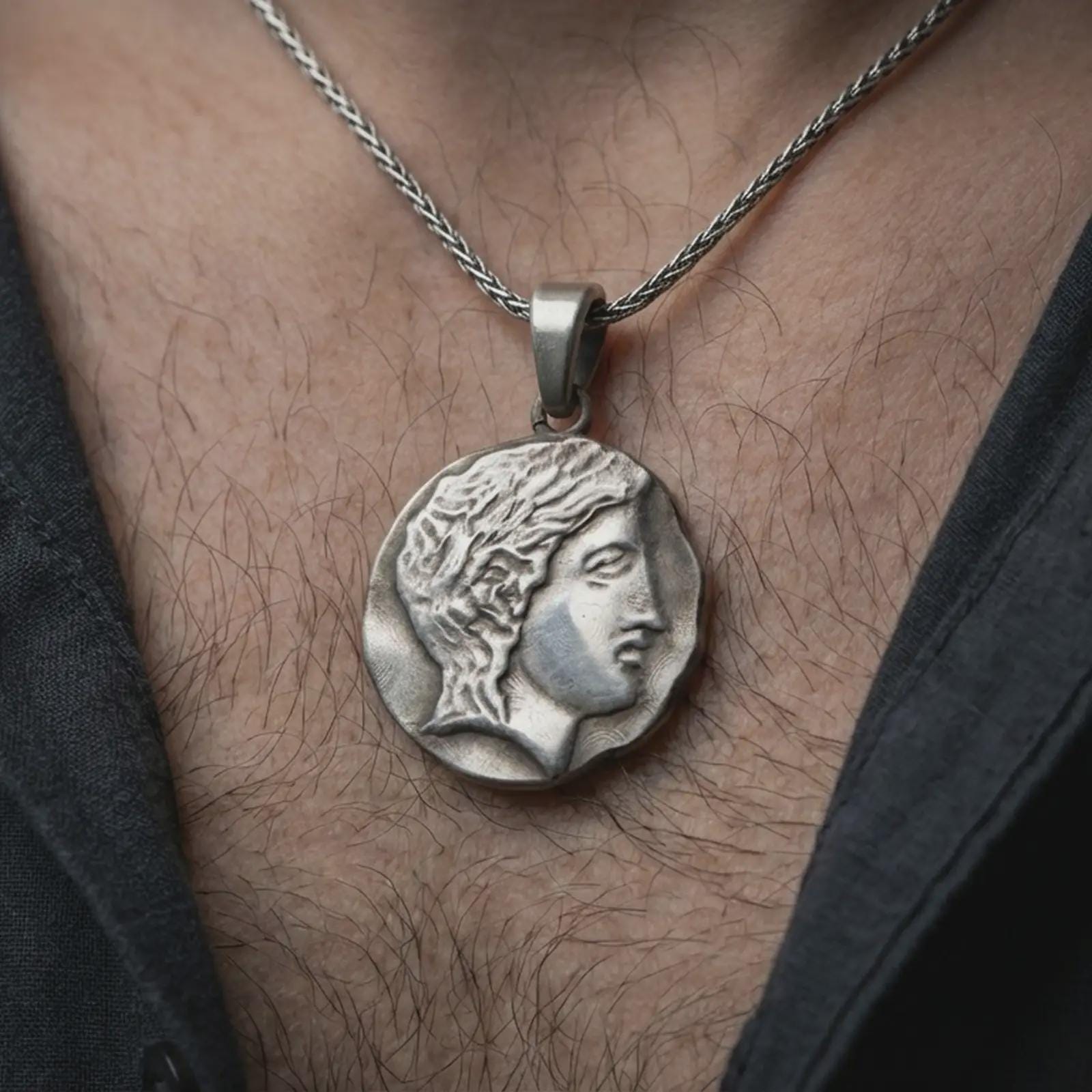 Oxidized ancient Greek coin pendant necklace worn on the neck, styled in a dark lifestyle image that presents the classical female portrait as a bold historical and artistic statement piece.